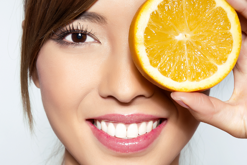 Woman with orange, beautiful skin, benefits of vitamin C, Jolanta's European Spa